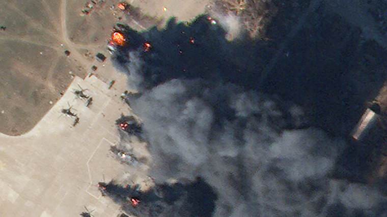 In a zoomed-in portion of the image, helicopters can be seen burning.
