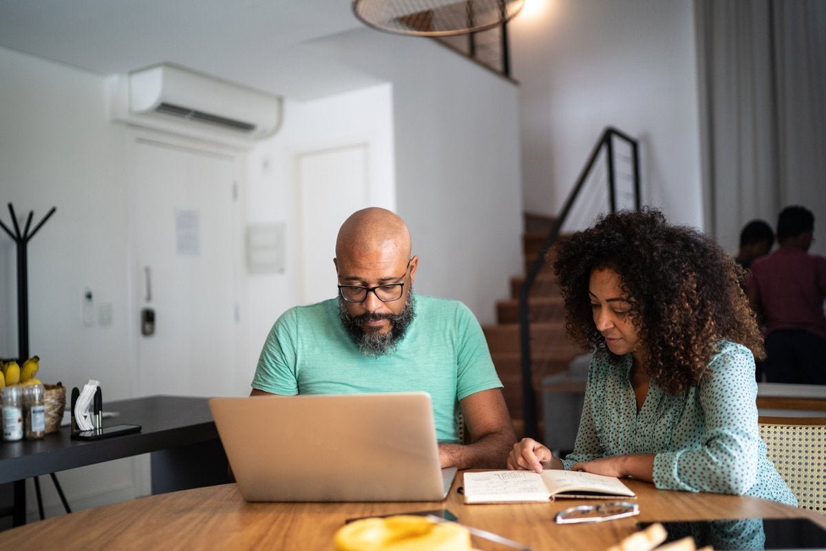 A couple does their personal finances using a laptop and notebook.